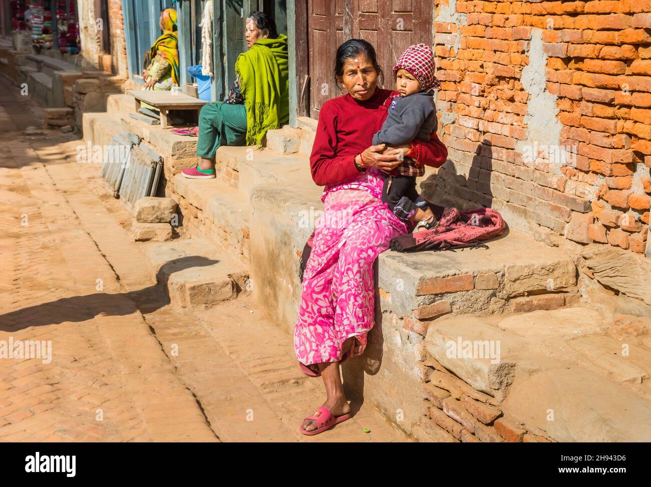 Woman and chils sitting in the streets of Bhaktapur, Nepal Stock Photo