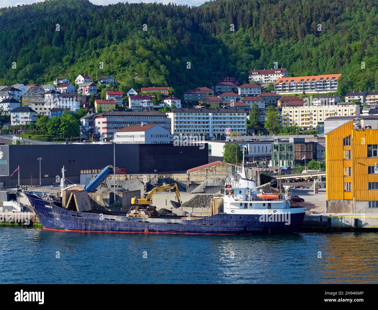 The Cabela, a General Cargo Vessel unloading its gravel cargo at a construction site on Bergen Ports Waterfront. Stock Photo