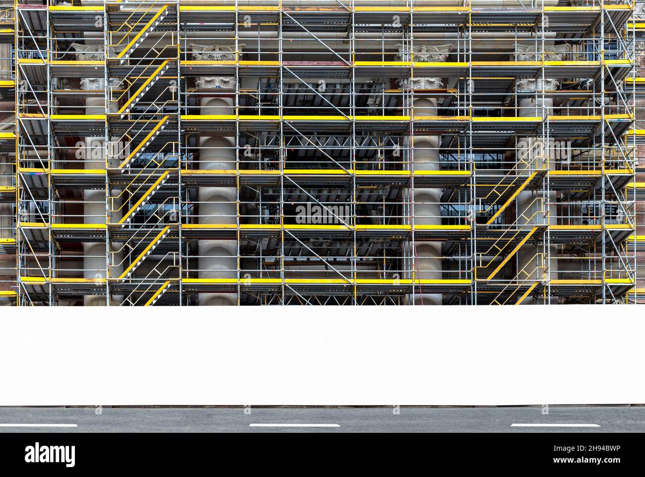 Construction site scaffolding with blank white fence, hoarding panel with copy space for branding or development project information Stock Photo