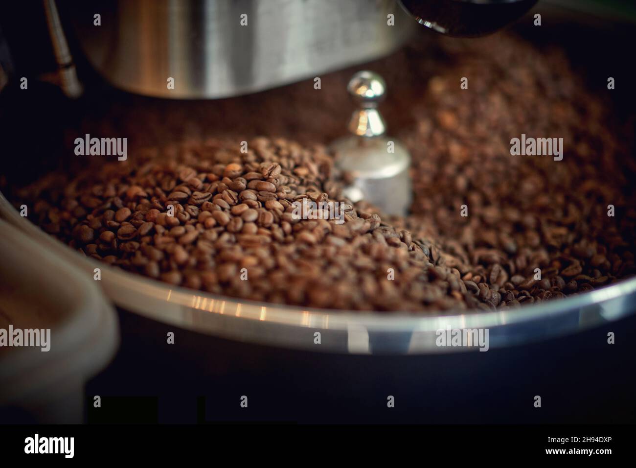 Aromatic and fragrant coffee beans are grinding in the grinder apparatus. Coffee, beverage, producing Stock Photo