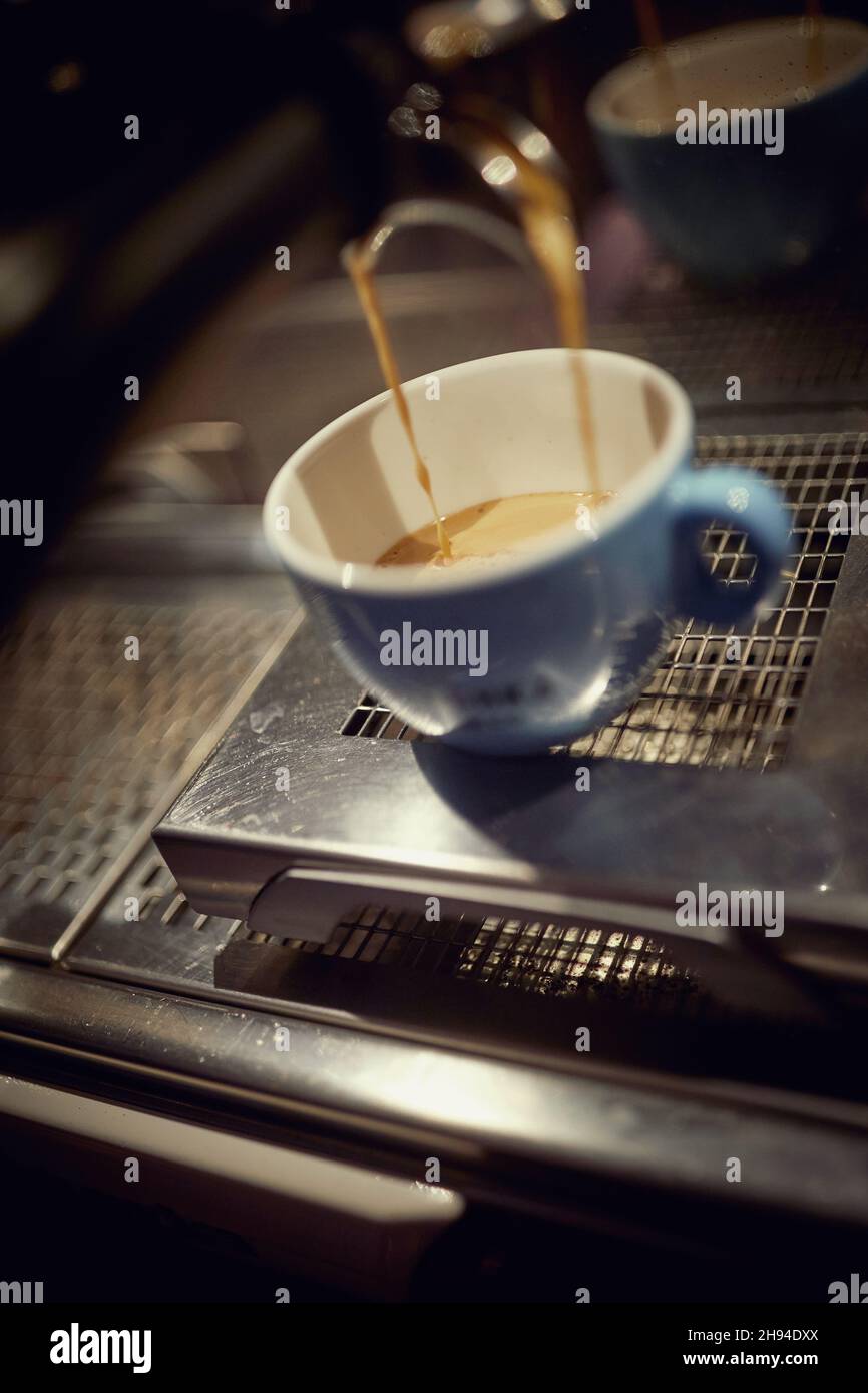 Close-up of an aromatic and fragrant espresso pouring into a cup in the apparatus. Coffee, beverage, bar Stock Photo