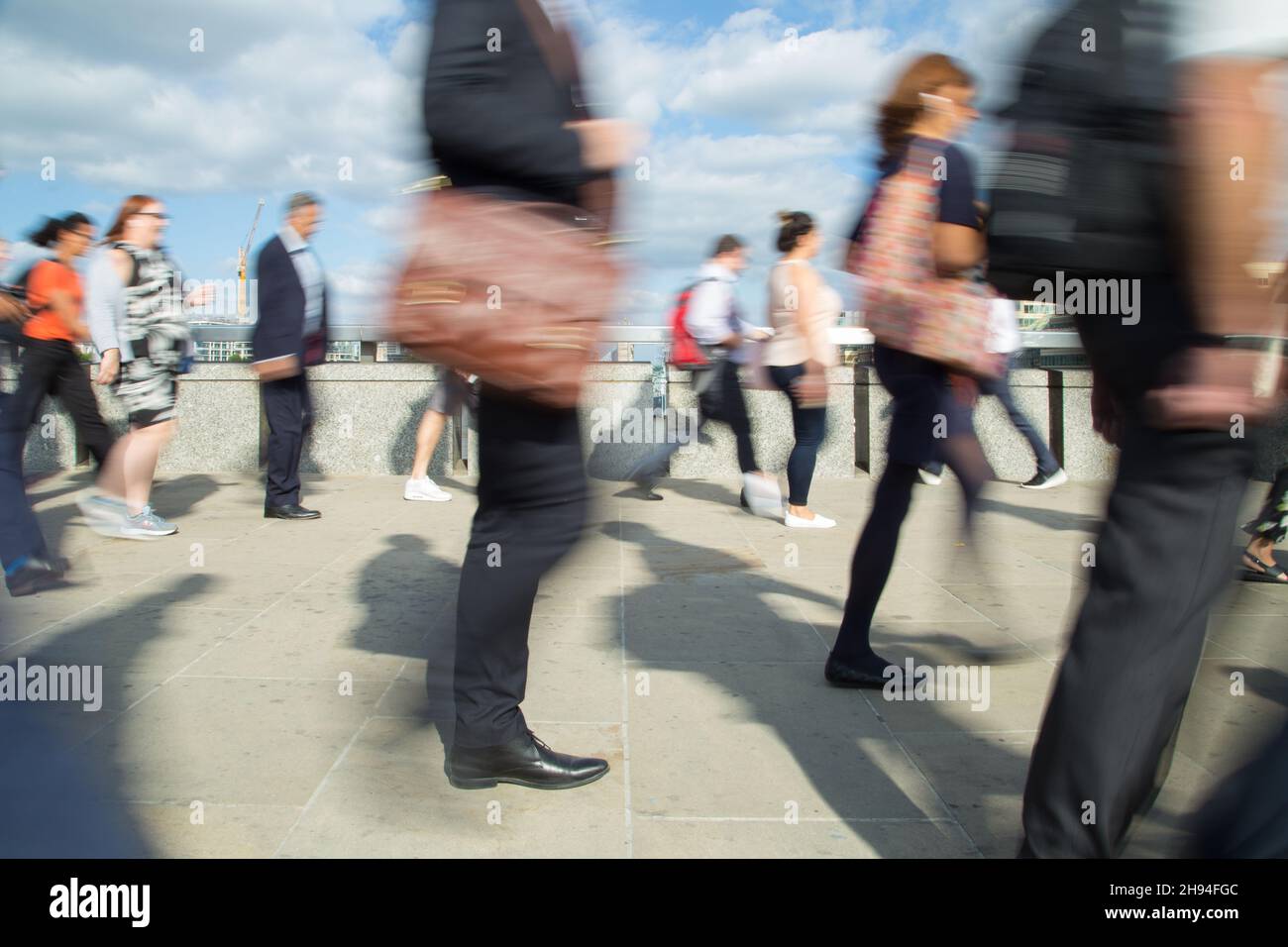 City workers walk across London Bridge at the end of the working day on their rush-hour commute home Stock Photo