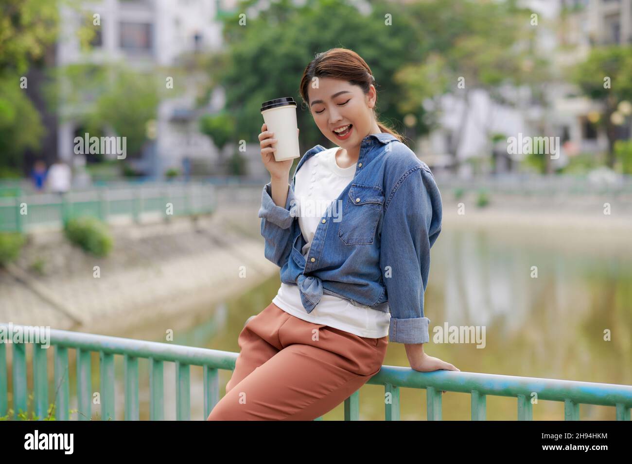 Half length portrait of smiling woman enjoying aroma coffee and free time in downtown Stock Photo