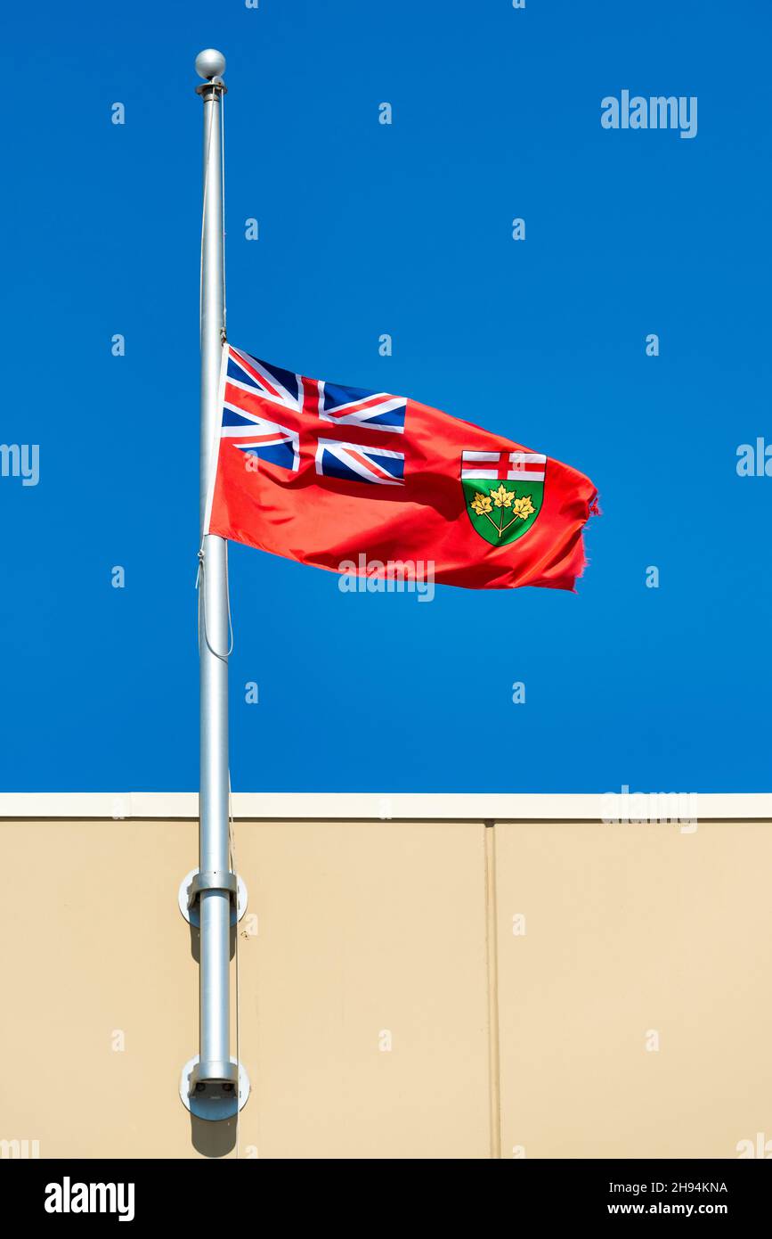 Flag of the Ontario province flying at half mast in a blue sky.Nov. 22, 2021 Stock Photo Alamy