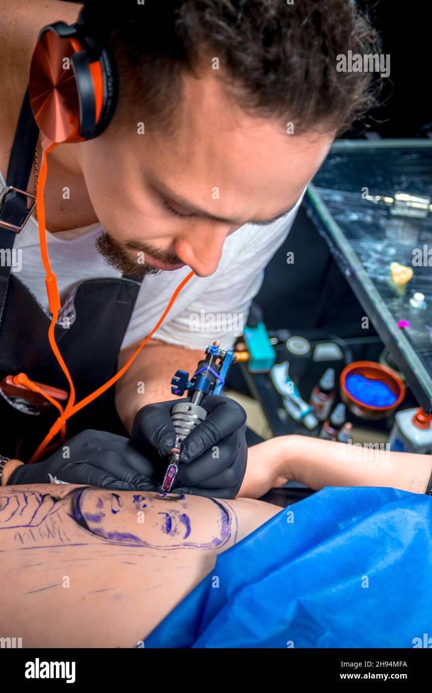 Tattooer working on professional tattoo machine gun in tattoo parlour