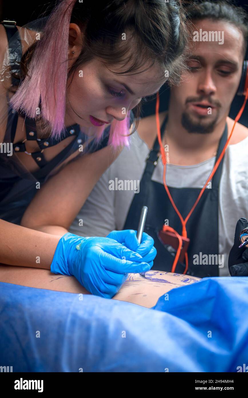Skin master demonstrates the process of getting tattoo in tattoo studio