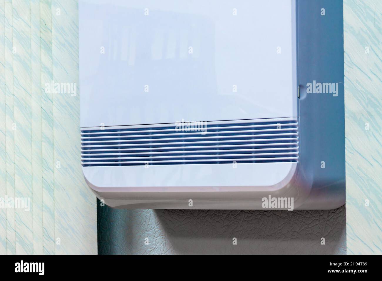 ventilation openings of a device in a white plastic case mounted on a wall in an office or apartment, selective focus Stock Photo