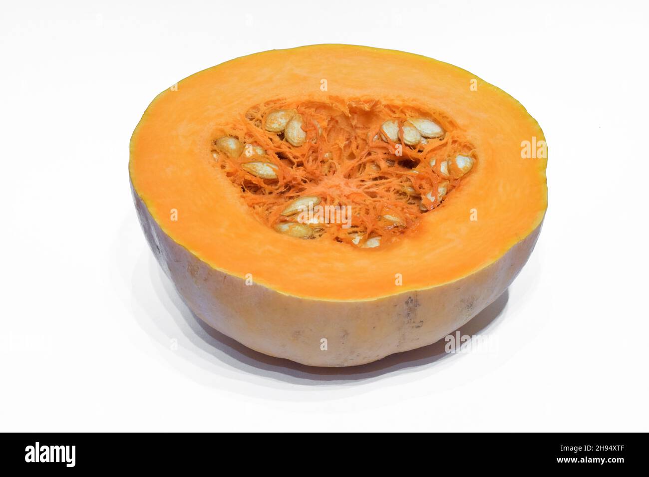 Fresh orange pumpkin cut in half with seeds, photographed against white clipping background Stock Photo