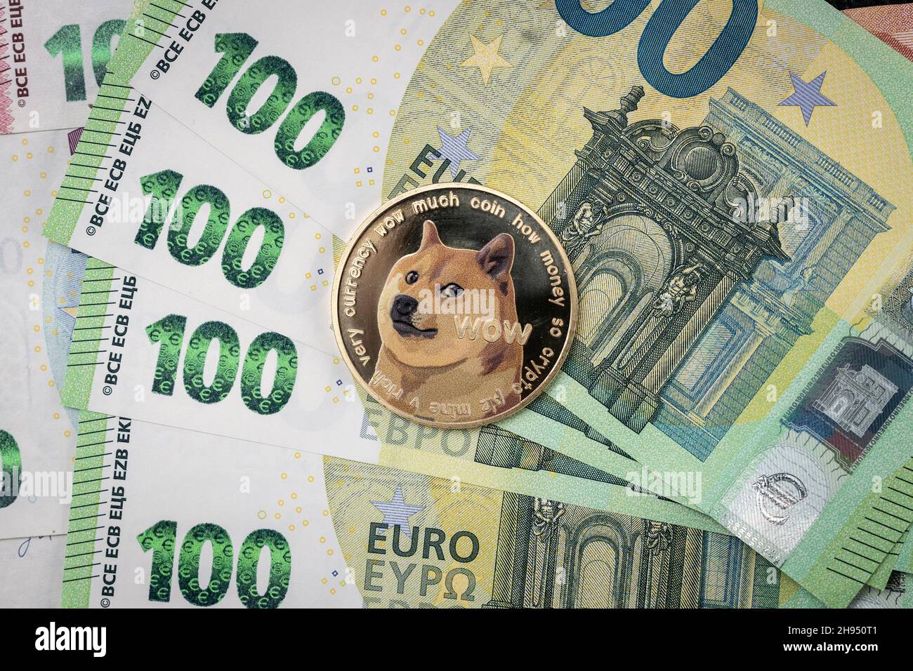 Dogecoin physical coin laying on top of 100 Euro bills. Stock Photo