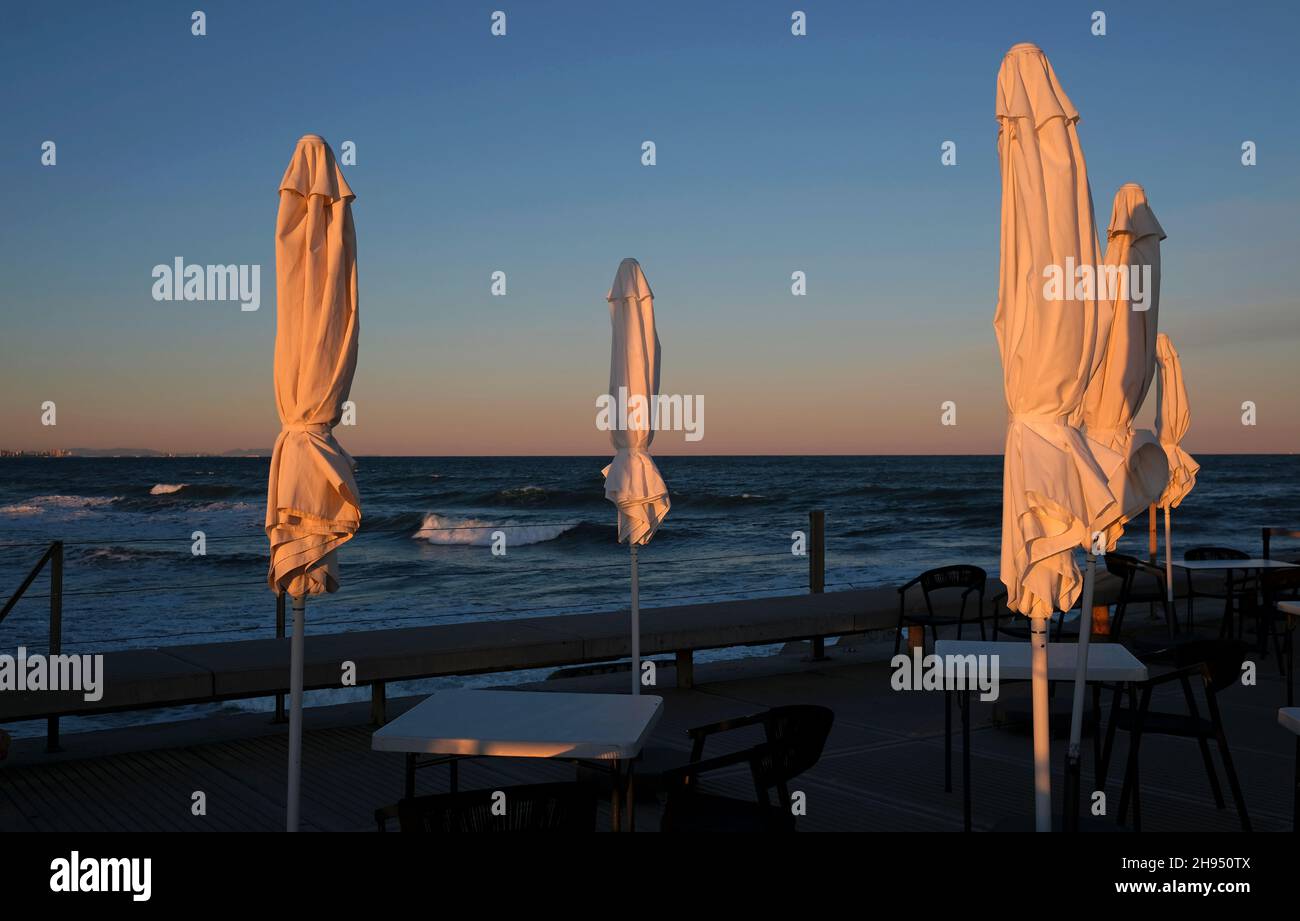 Closed umbrellas at a beach bar in Valencia in wintertime Stock Photo