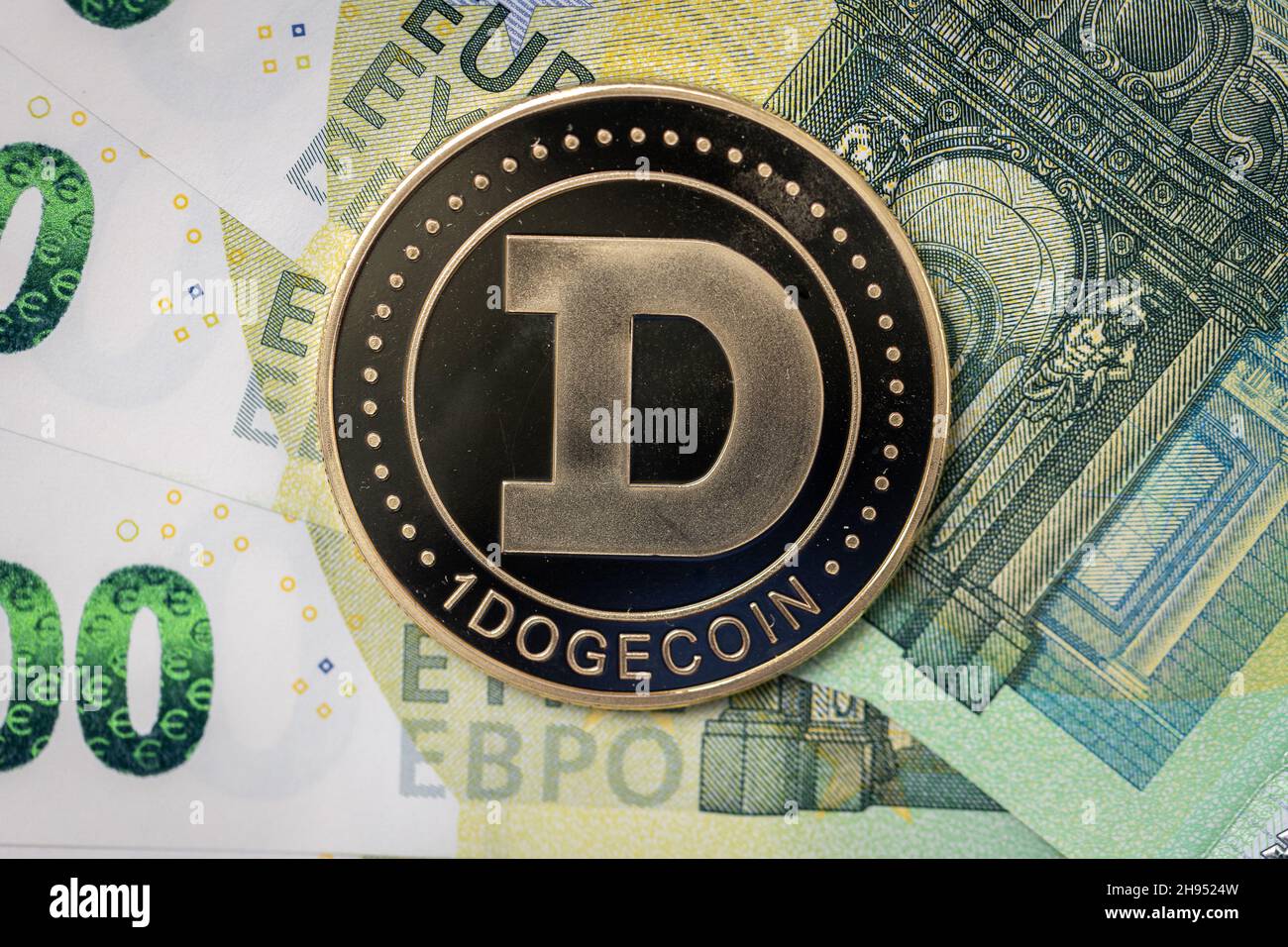 Dogecoin physical coin laying on top of 100 Euro bills. Stock Photo