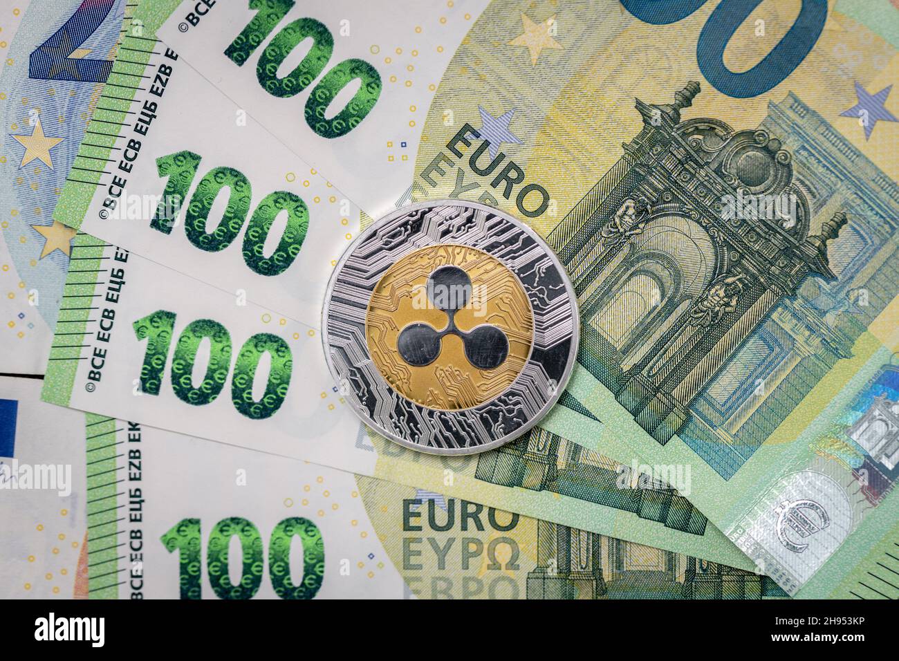 Ripple XRP physical coin laying on top of 100 Euro bills. Stock Photo