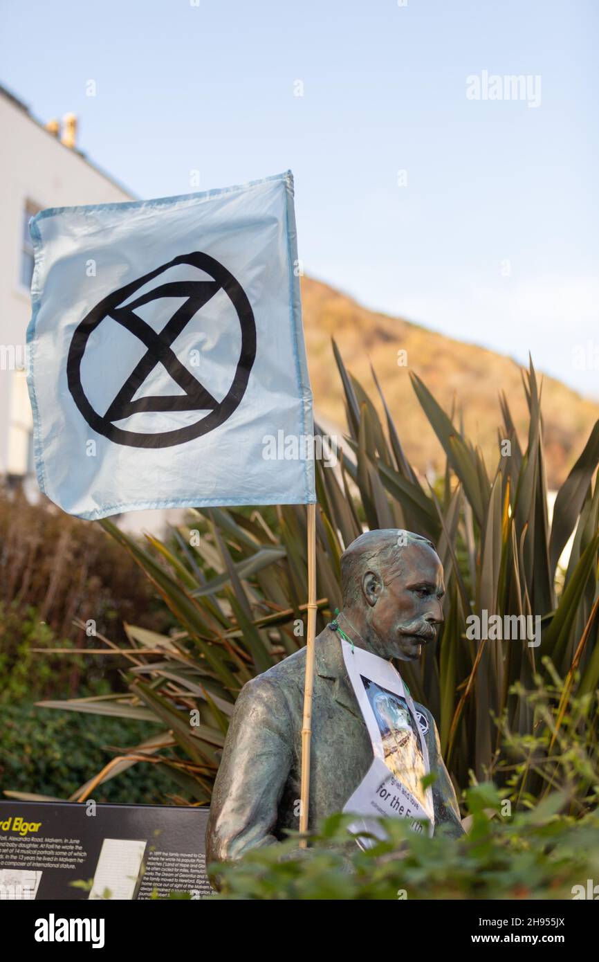 Great Malvern, Worcestershire, UK. 4th Dec, 2021. An Extinction Rebellion flag is attached to the bronze statue of Sir Edward Elgar in Bell Vue Terrace Island, Great Malvern, Worcestershire. The famous English composer is an unwitting supporter of the climate activists XR Malvern aims, as his statue bears the XR flag and a poster which reads 'grief and love for the Earth'. Credit: Peter Lopeman/Alamy Live News Stock Photo