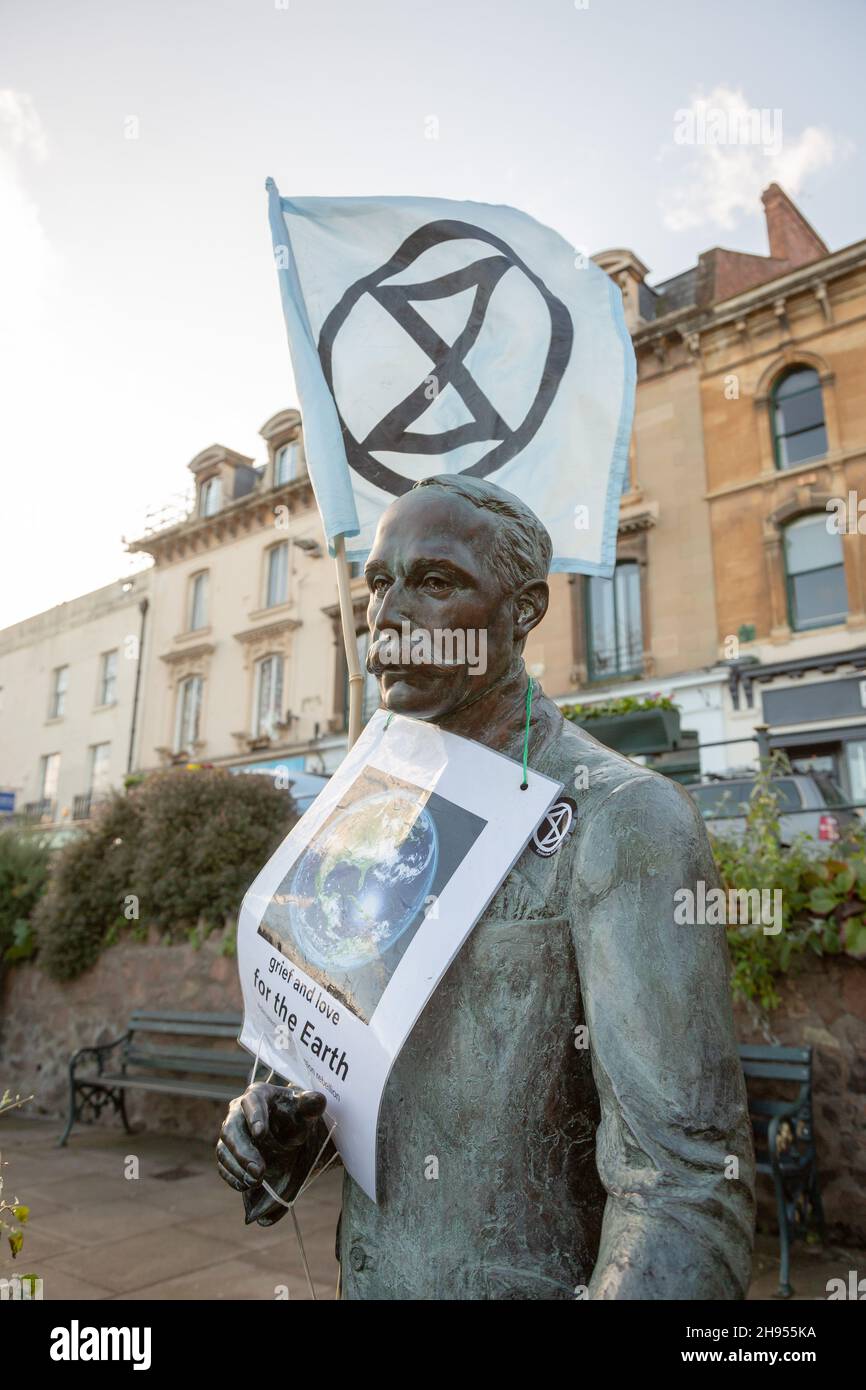 Great Malvern, Worcestershire, UK. 4th Dec, 2021. An Extinction Rebellion flag is attached to the bronze statue of Sir Edward Elgar in Bell Vue Terrace Island, Great Malvern, Worcestershire. The famous English composer is an unwitting supporter of the climate activists XR Malvern aims, as his statue bears the XR flag and a poster which reads 'grief and love for the Earth'. Credit: Peter Lopeman/Alamy Live News Stock Photo