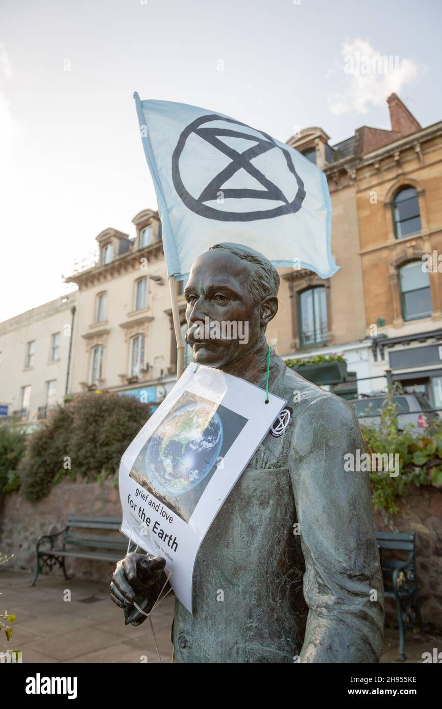 Great Malvern, Worcestershire, UK. 4th Dec, 2021. An Extinction Rebellion flag is attached to the bronze statue of Sir Edward Elgar in Bell Vue Terrace Island, Great Malvern, Worcestershire. The famous English composer is an unwitting supporter of the climate activists XR Malvern aims, as his statue bears the XR flag and a poster which reads 'grief and love for the Earth'. Credit: Peter Lopeman/Alamy Live News Stock Photo