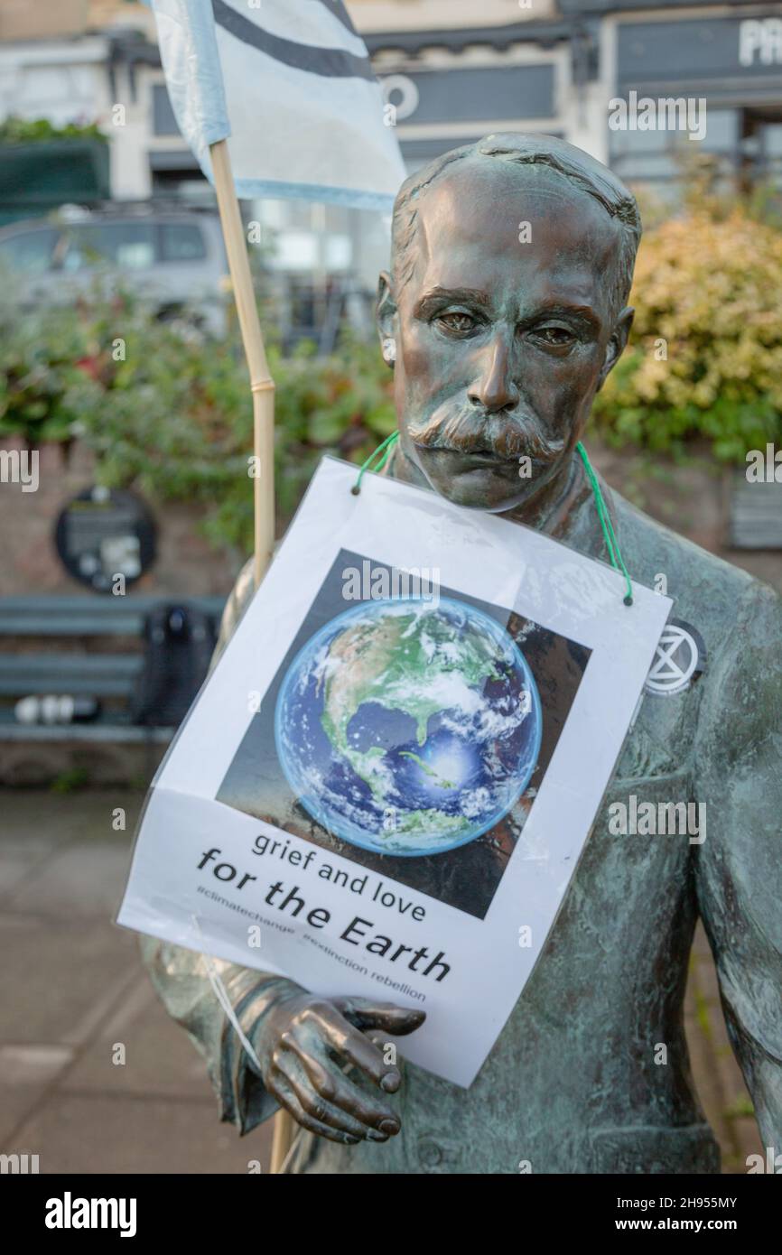 Great Malvern, Worcestershire, UK. 4th Dec, 2021. An Extinction Rebellion flag is attached to the bronze statue of Sir Edward Elgar in Bell Vue Terrace Island, Great Malvern, Worcestershire. The famous English composer is an unwitting supporter of the climate activists XR Malvern aims, as his statue bears the XR flag and a poster which reads 'grief and love for the Earth'. Credit: Peter Lopeman/Alamy Live News Stock Photo