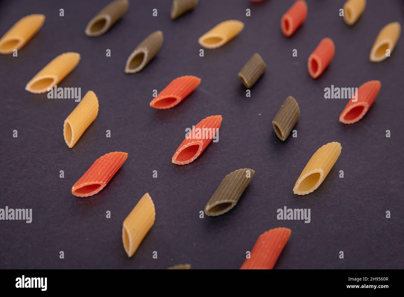 Colored raw penne pasta on dark background Stock Photo - Alamy