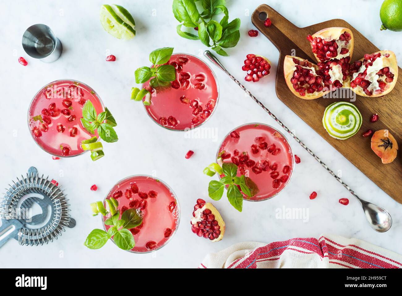 Pomegranate Basil Martini Cocktails with Lime Twist in Coupe Glasses on