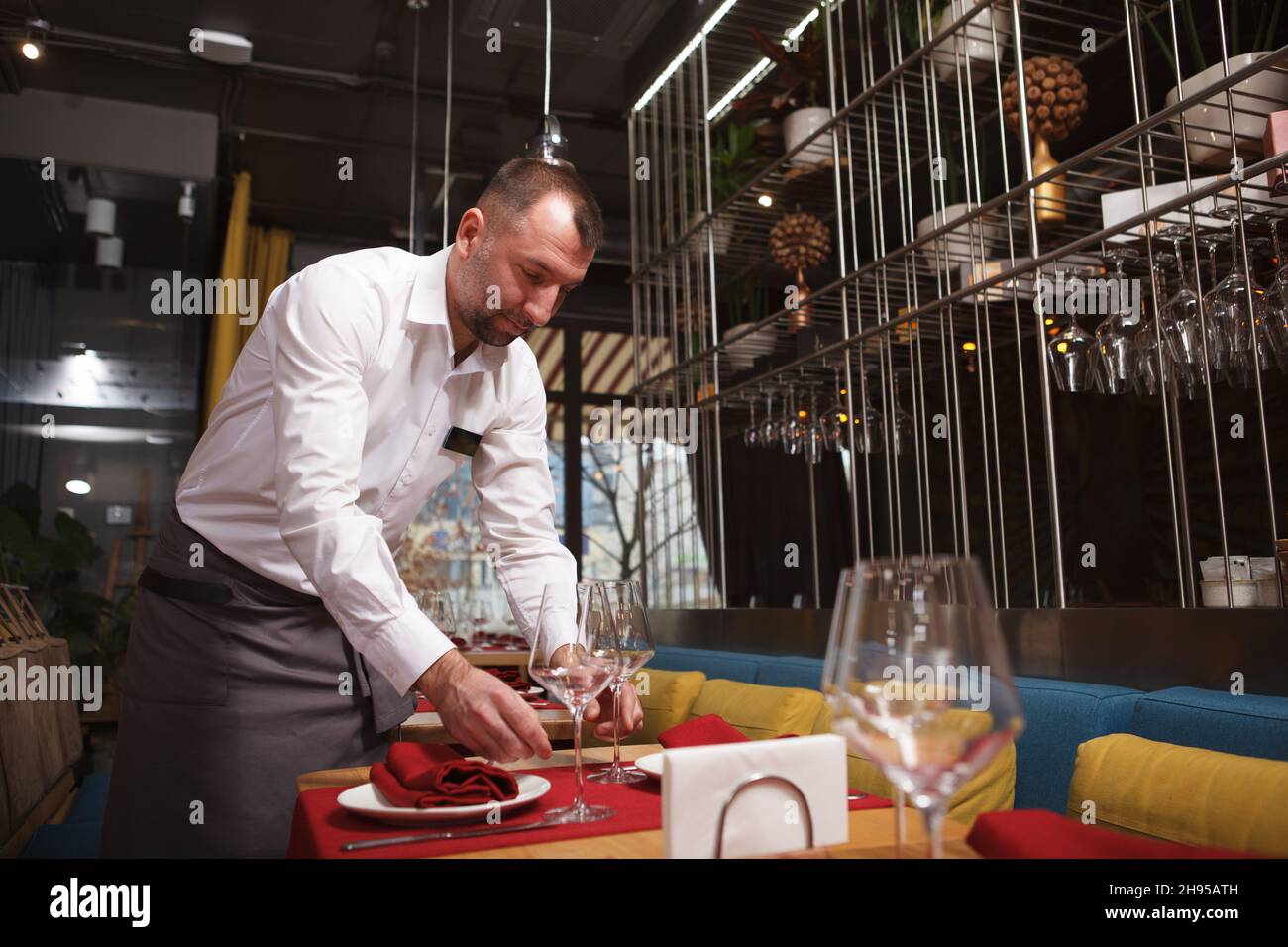 Low angle shot of a professional waiter preparing tables for guests at ...