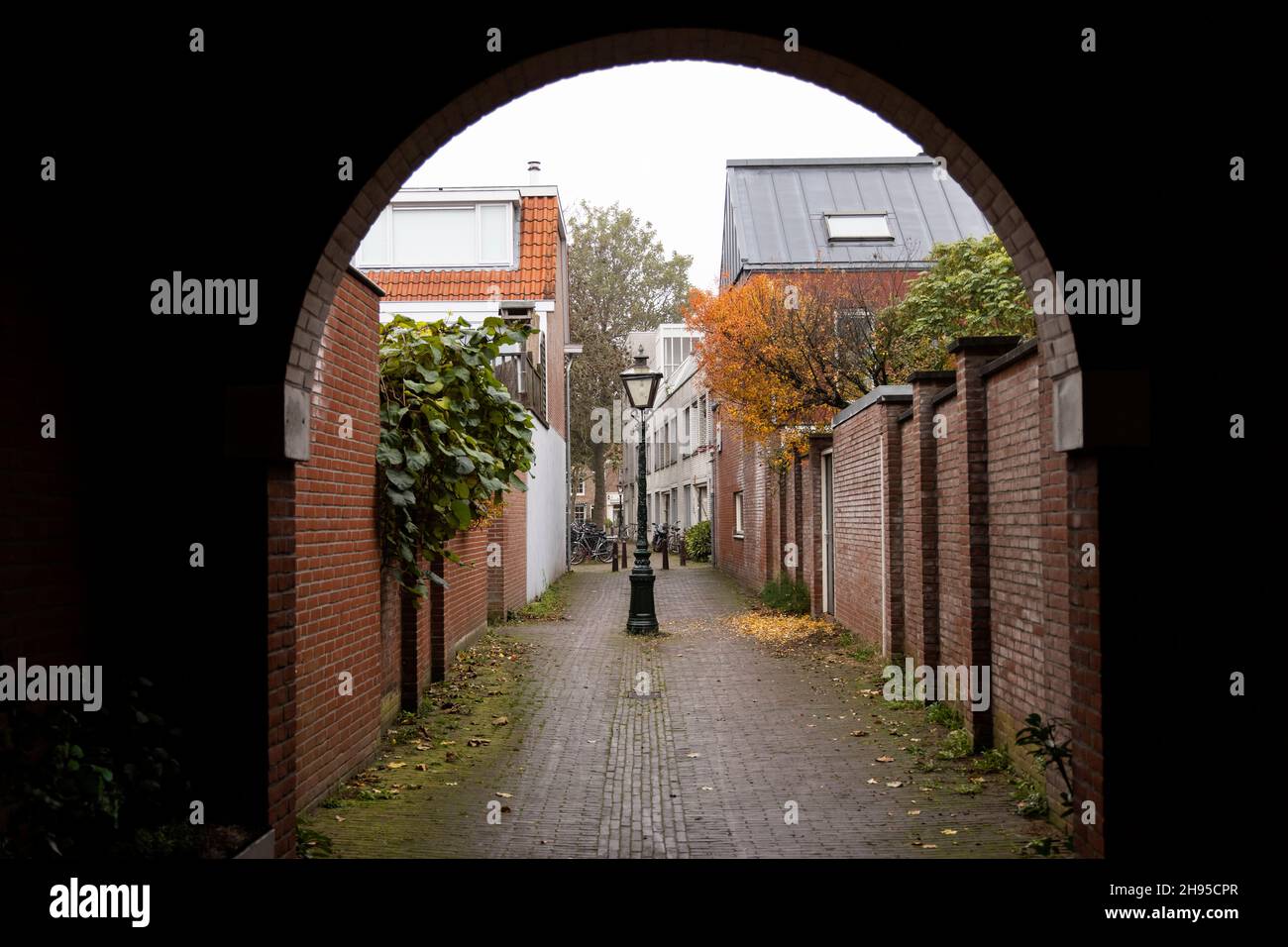 Looking through an arched alley walkway on Cananefatenpoort on a fall day in Leiden, Netherlands. Stock Photo