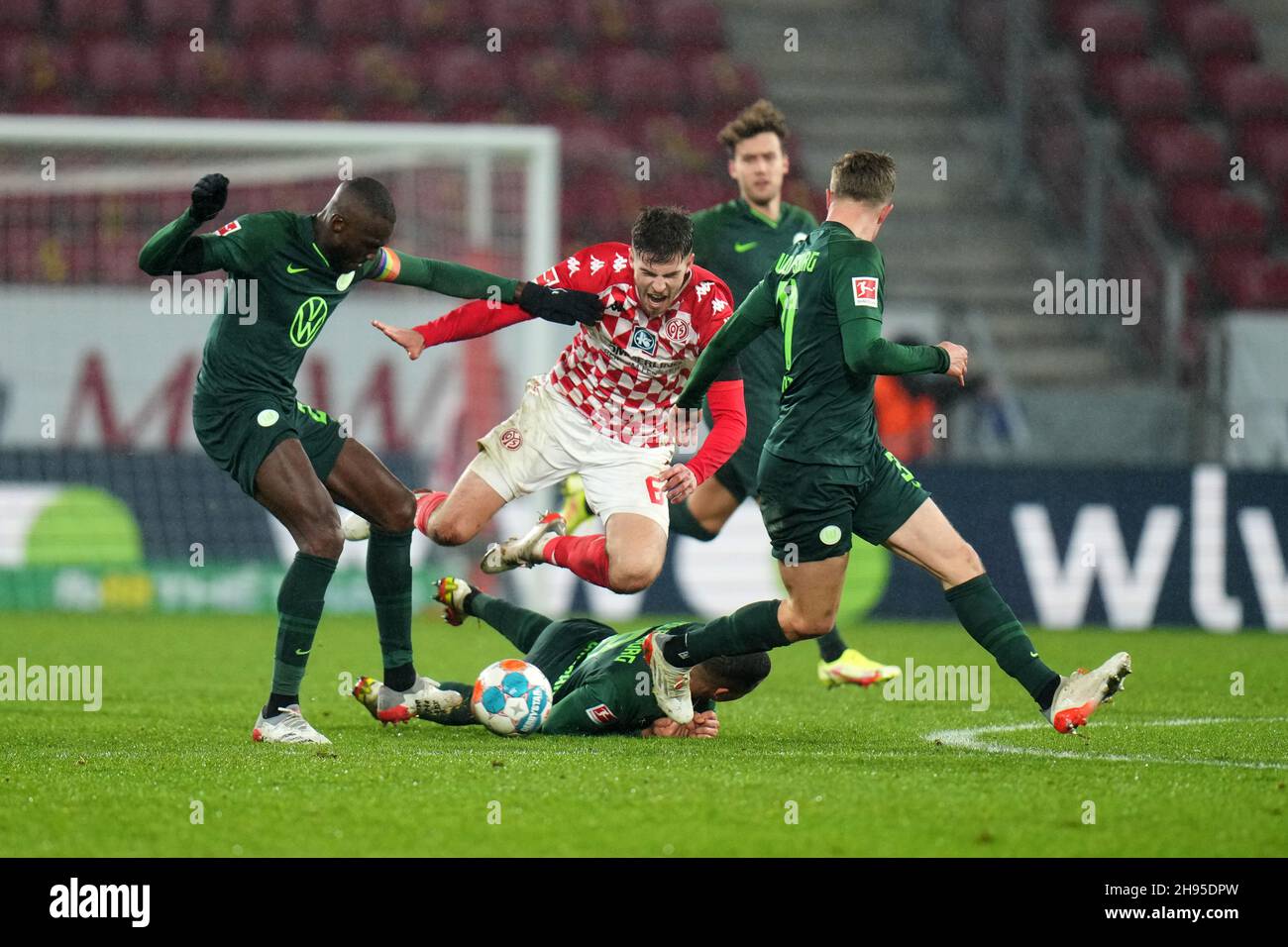 Mainz, Germany. 04th Dec, 2021. Football: Bundesliga, FSV Mainz 05 - VfL Wolfsburg, Matchday 14, Mewa Arena. Mainz's Anton Stach (M) is rudely stopped by Wolfsburg's Josuha Guilavogui (l), Lukas Nmecha (on the ground) and Yannick Gerhardt. Credit: Thomas Frey/dpa - IMPORTANT NOTE: In accordance with the regulations of the DFL Deutsche Fußball Liga and/or the DFB Deutscher Fußball-Bund, it is prohibited to use or have used photographs taken in the stadium and/or of the match in the form of sequence pictures and/or video-like photo series./dpa/Alamy Live News Stock Photo