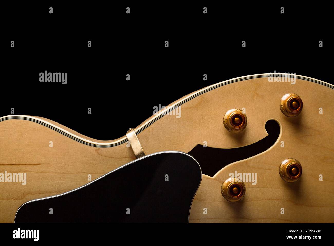 Pale wood guitar on bottom of image with buttons and white pickguard Stock Photo