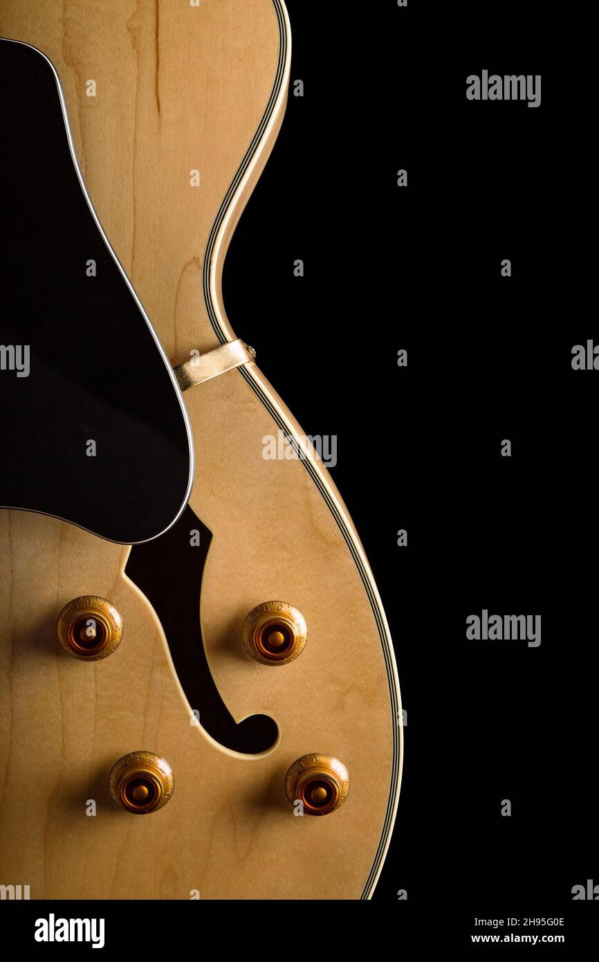 Pale wood guitar on left side of image with buttons and white pickguard of image with buttons and white pickguard Stock Photo