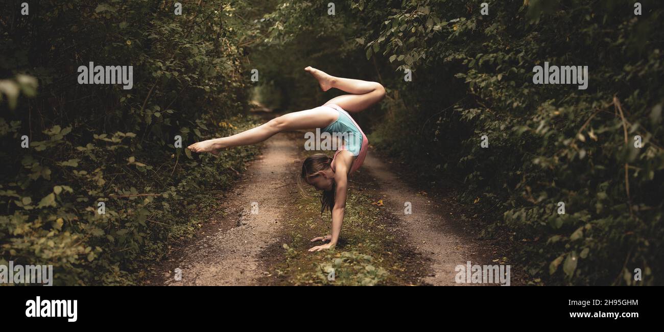 Beautiful young female girl performs acrobatics gymnastic exercises in a forest. Amazing nature landscape. High quality photo Stock Photo