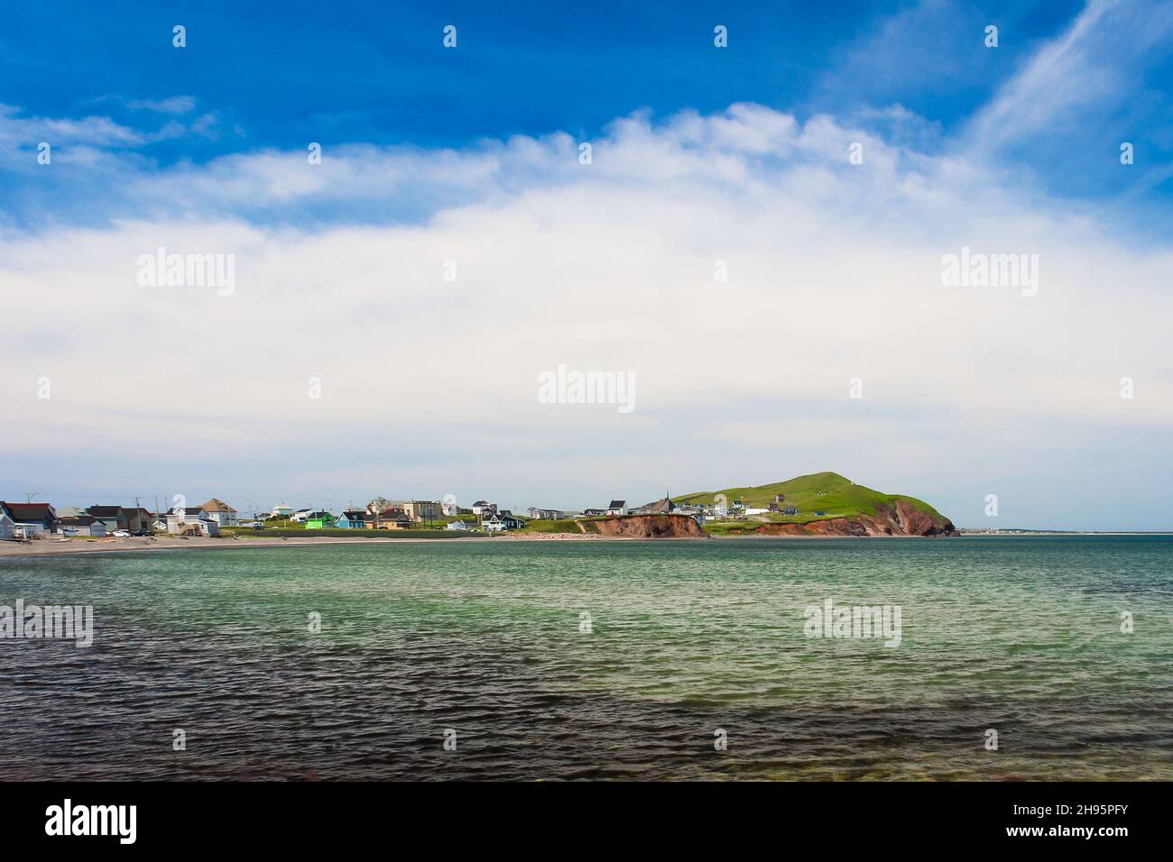 Distant sandy beach with houses, blue sky and sea as foreground at ...