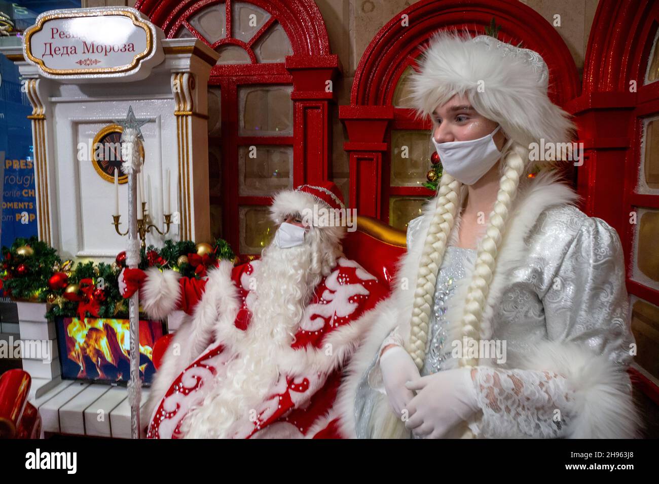 Moscow, Russia. 4th of December, 2021 Father Frost (Russian: Ded Moroz) and Snegurochka wearing face masks greet guests at the residence of Father Frost in the hall of the Central Children's Store on Lubyanka in central Moscow during novel coronavirus COVID-19 infection in Russia Stock Photo