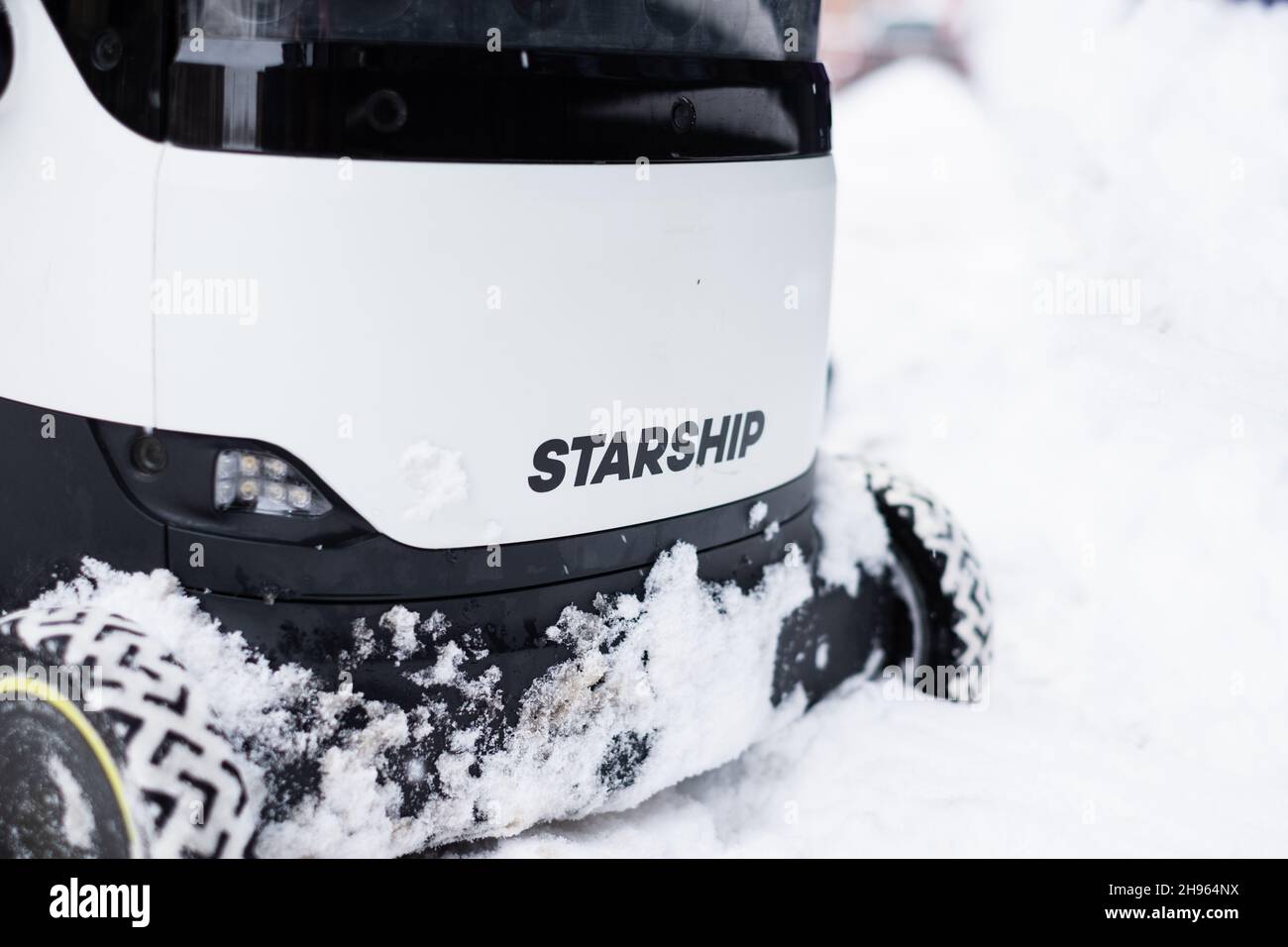 Tallinn, Estonia - December 4, 2021: Starship Technologies autonomous drone vehicle driving in snow during winter. Self driving delivery robot. Stock Photo