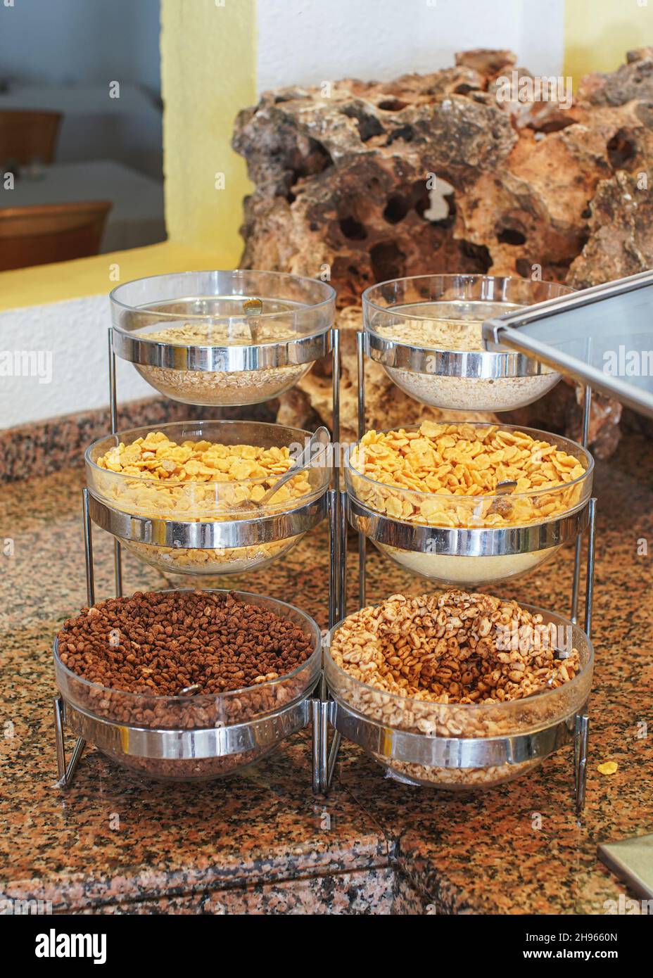 Corn, cereals and rice flakes in glass bowls displayed at restaurant breakfast buffet table
