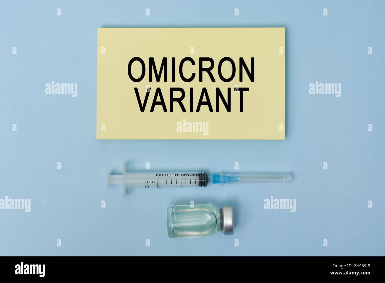 Omicron variant text on piece of paper. New covid variant from South Africa. Vaccine vial, syringe and face mask on bright colored background. New Stock Photo
