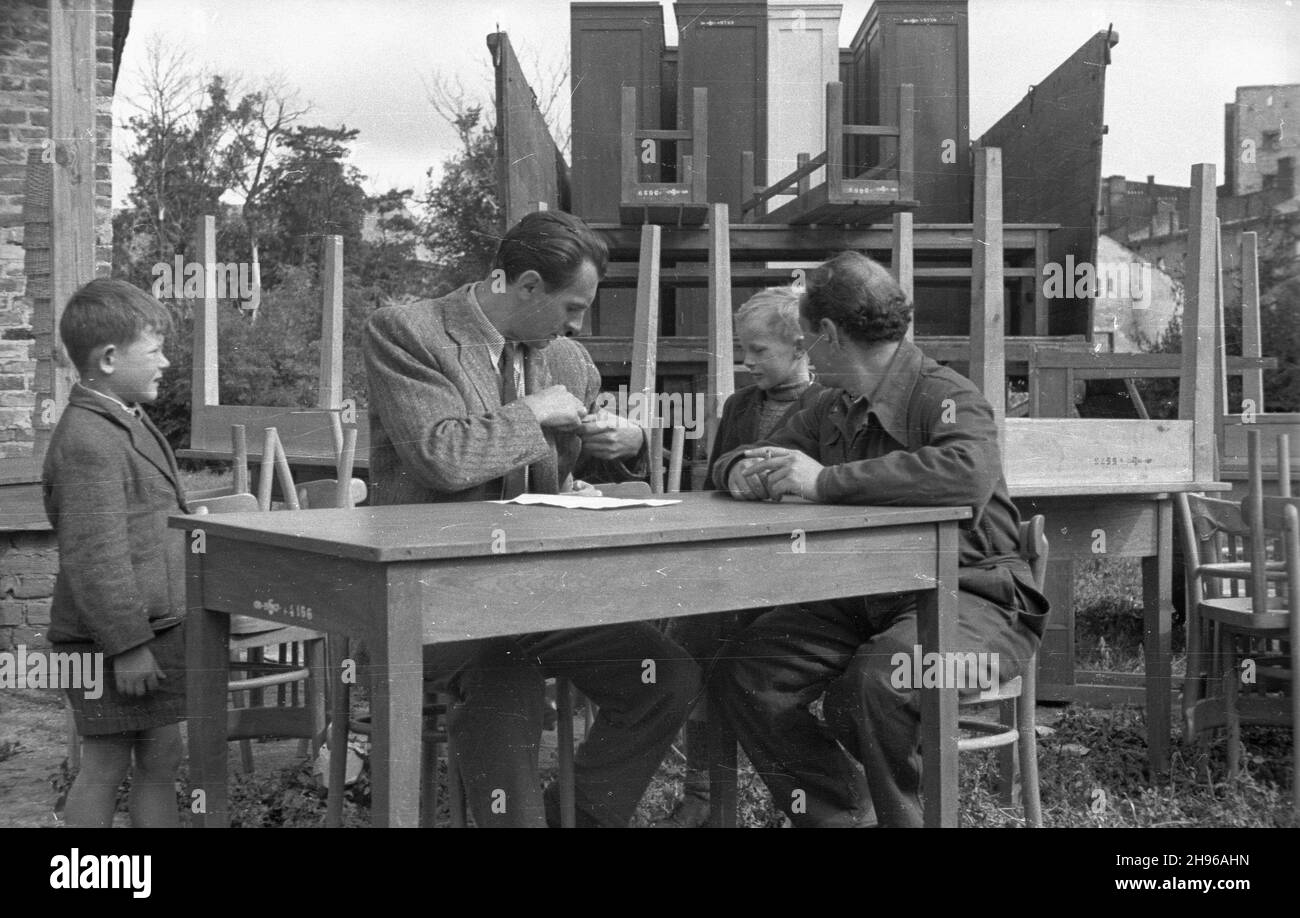 Warszawa, 1947-08. Nowo wybudowana szko³a podstawowa w Ogrodzie Saskim. Nz. wizyta ekipy Polskiej Kroniki Filmowej, przy stole siedzi¹: sprawozdawca radiowy Tadeusz Pyszkowski, operator kamery W³adys³aw Forbert (P). bb/gr PAP Dok³adny dzieñ wydarzenia nieustalony. Warsaw, Aug. 1947. Newly built primary school in the Saski Garden. Pictured: a visit by a crew of the Polish Film Chronicle. At the table: commentator Tadeusz Pyszkowski, camera-man Wladyslaw Forbert (right). bb/gr PAP Stock Photo