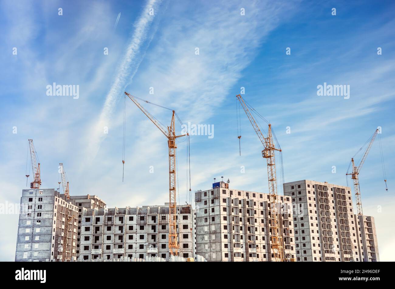 High-rise building under construction. The site with cranes against blue sky Stock Photo