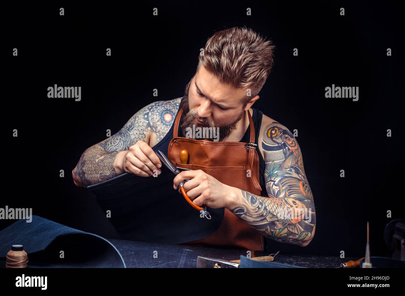 Leather Tanner cuts out leather goods Stock Photo