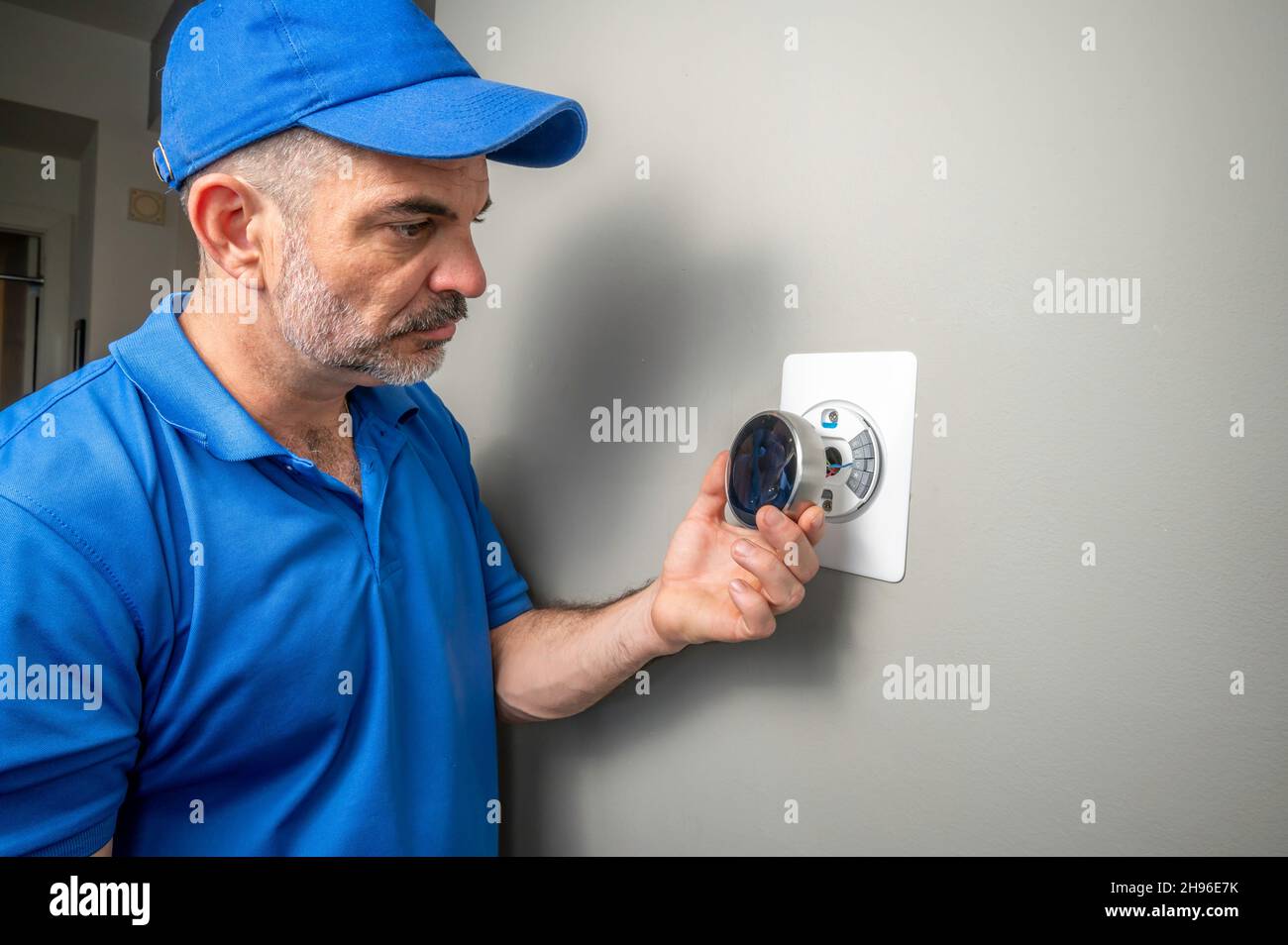 HVAC Technician Installing a Smart Thermostat Inside of a Home Stock Photo