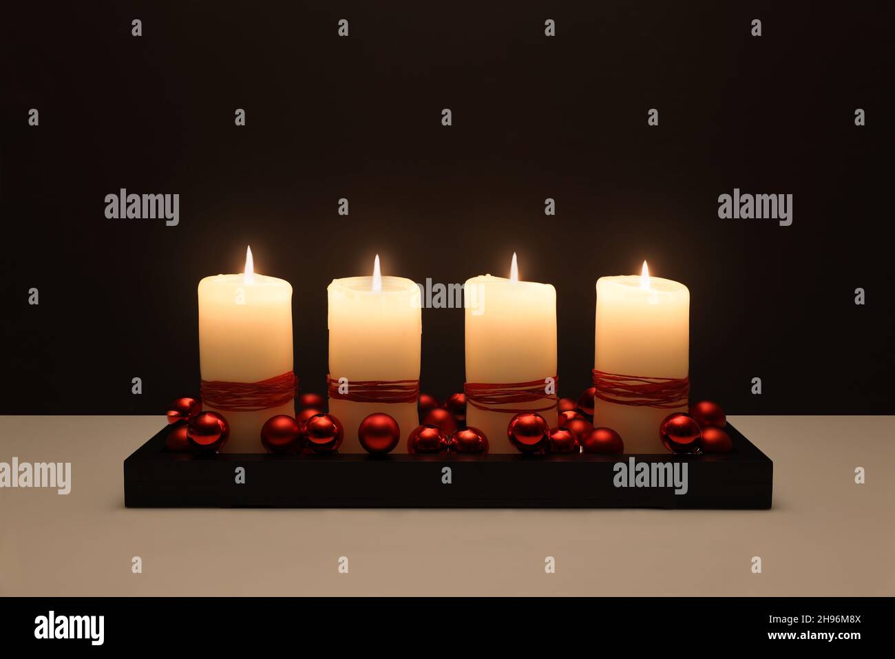 Four white candles in front of black background in Advent Stock Photo