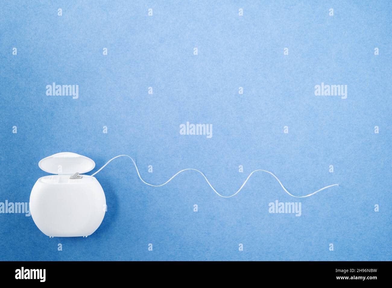 Container with dental floss. Floss blue background. Open dental floss