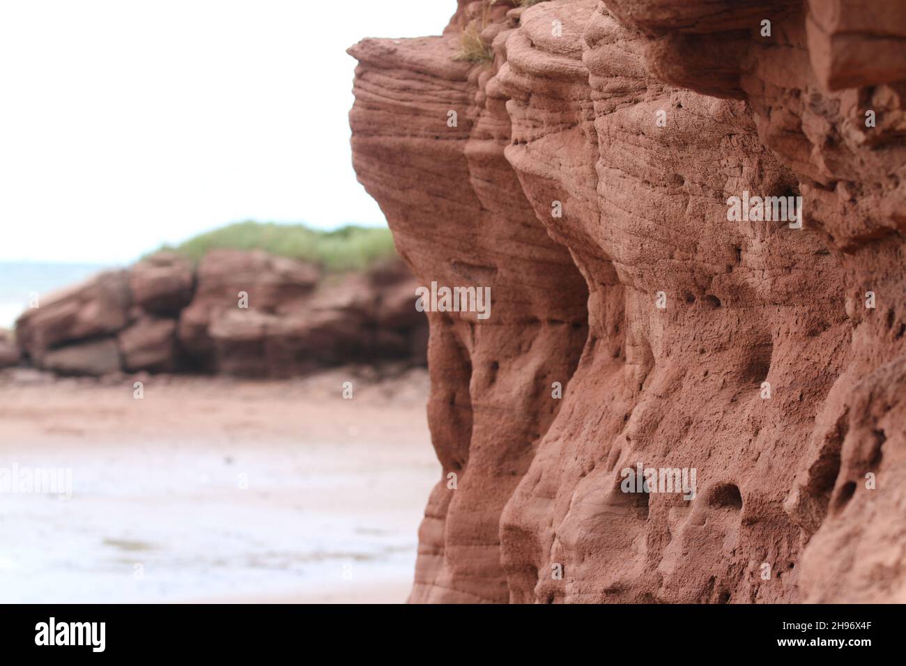 Wind erosion of ruby-red sandstone cliffs and coveted sandy beaches Stock Photo