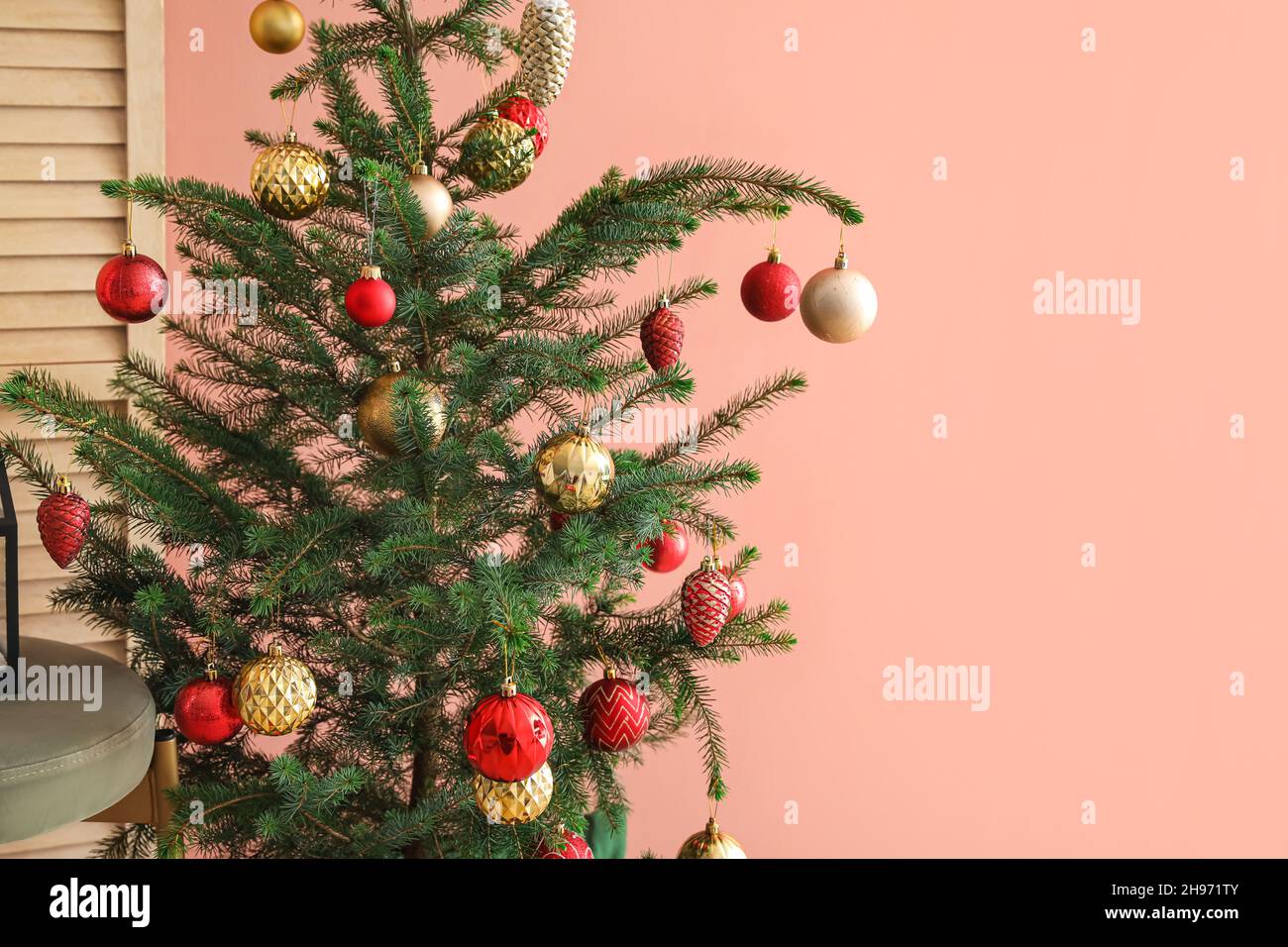 Christmas tree decorated with beautiful balls near color wall Stock ...