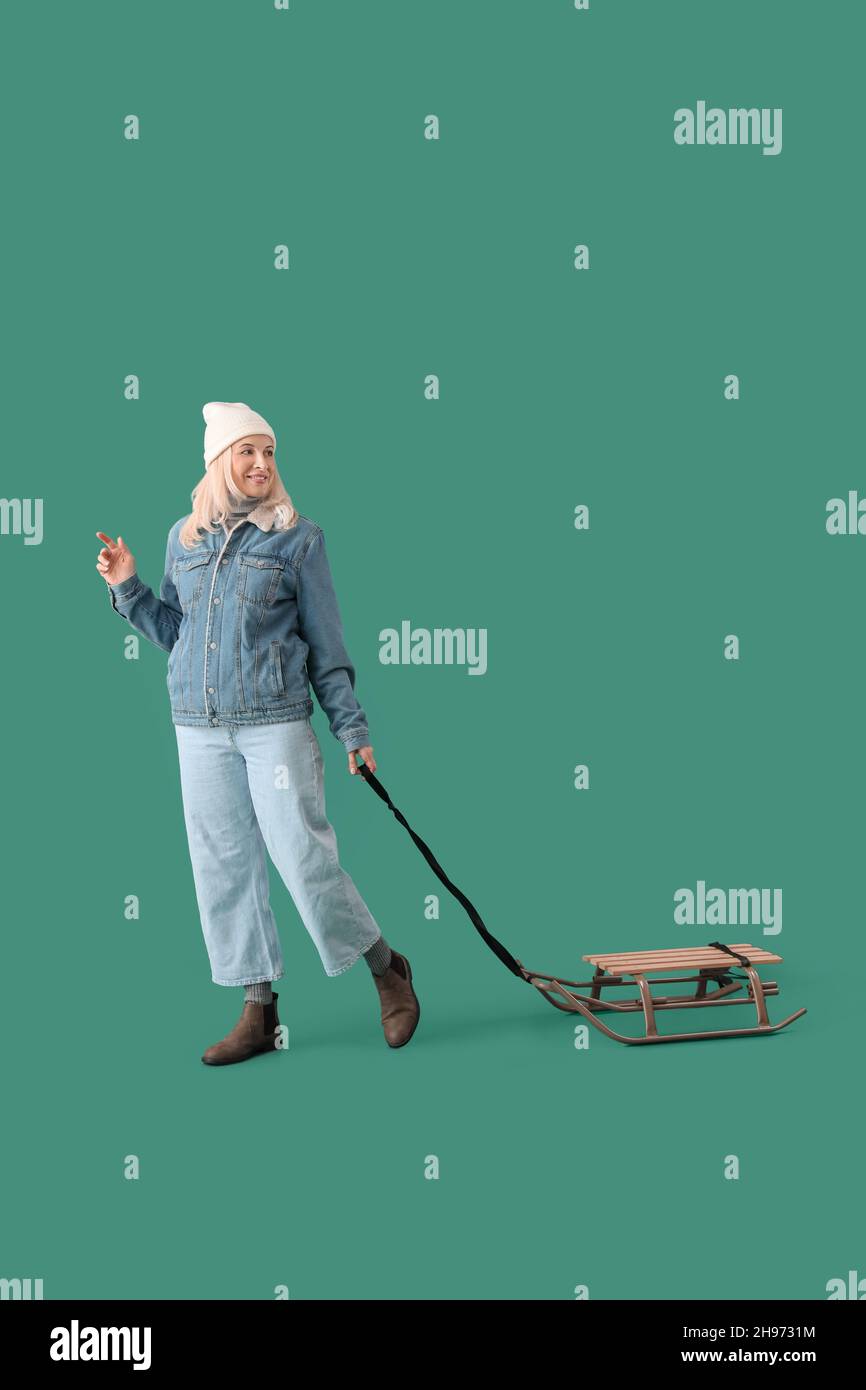 Beautiful mature woman with sled on color background Stock Photo Alamy
