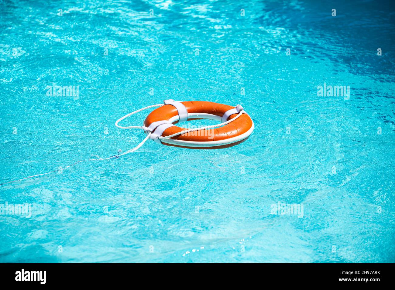 Lifebelt on sea or pool. Orange inflatable ring floating in blue water