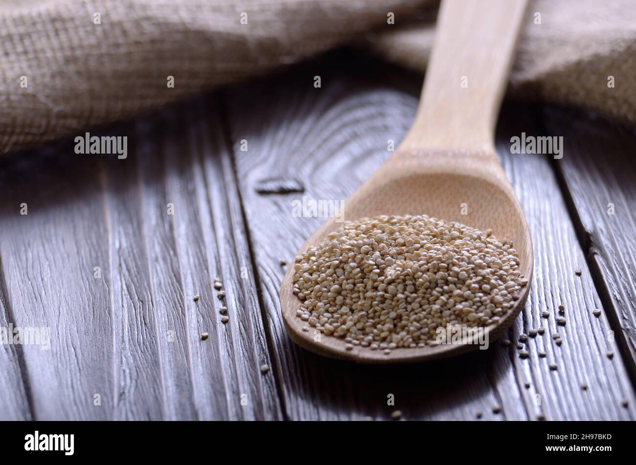 Raw organic superfood gluten free quinoa seeds in wooden spoon on kitchen table closeup Stock Photo