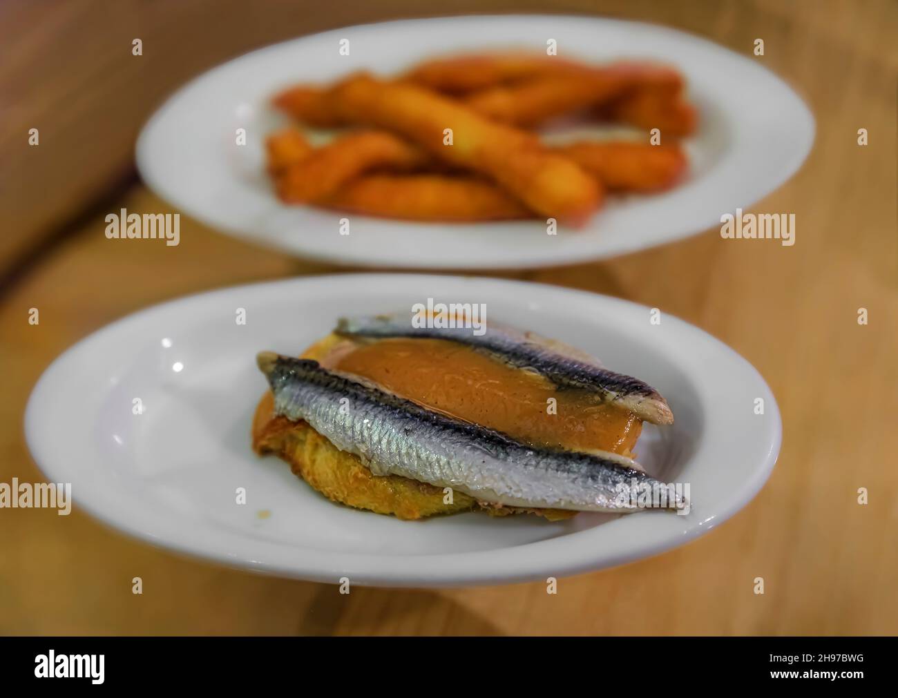 Spanish pintxos or tapas of anchovies on foie gras with apple compote and fried calamari in a