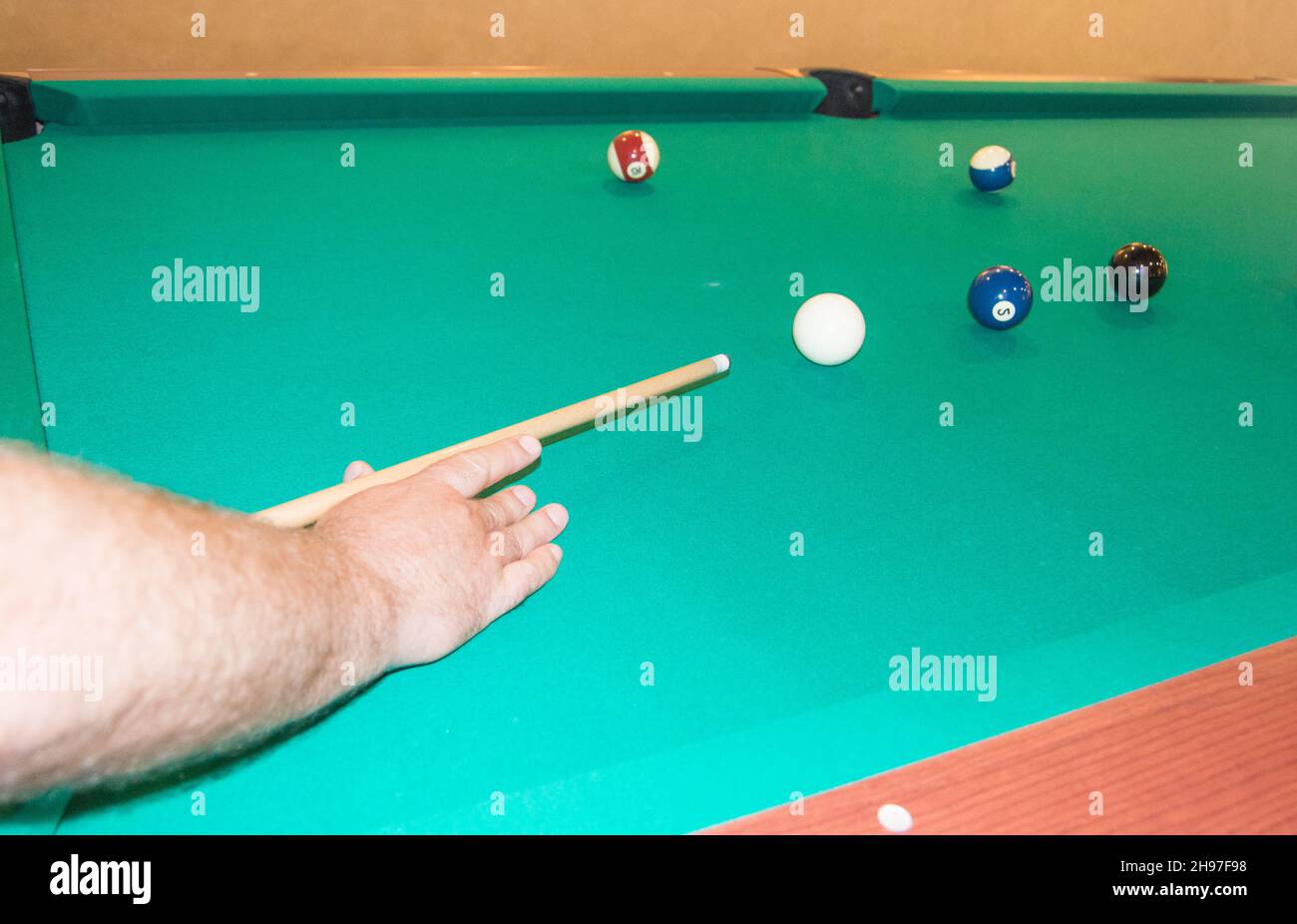A closeup of a billiard table with balls pointing the athlete's hands before hitting Stock