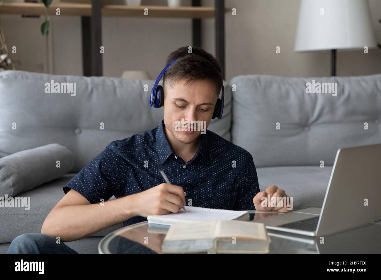 Focused young adult student guy wearing wireless earphones Stock Photo