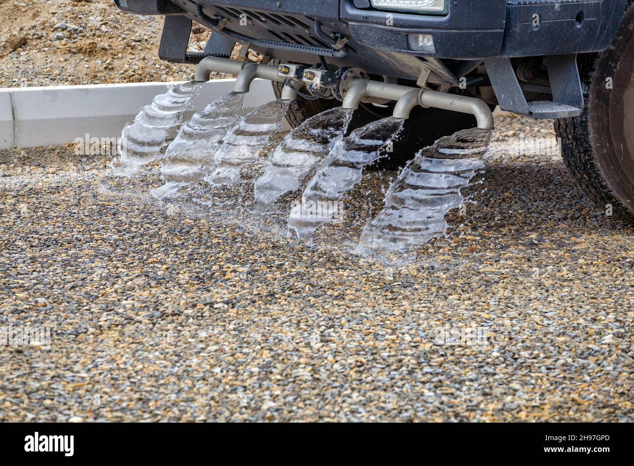Water truck spraying new gravel road and prepare for asphalting. Truck