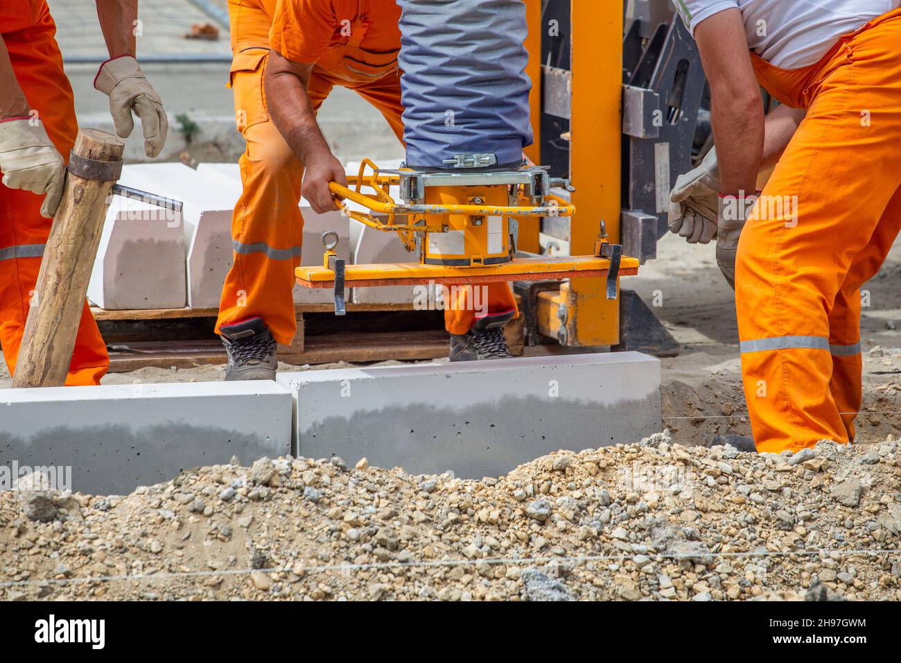 Workers using machine to set the concrete curbs. Concrete kerb