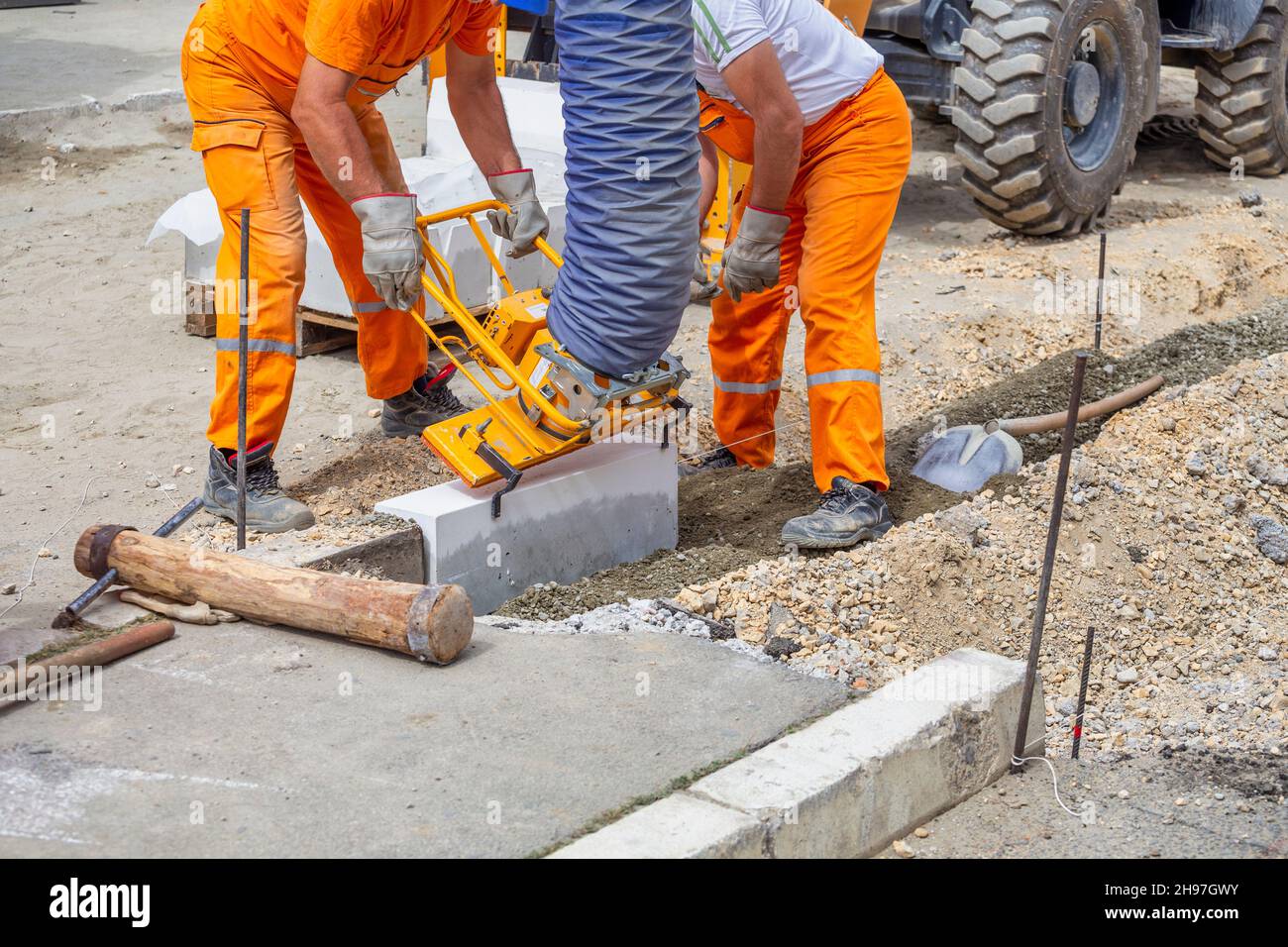 Workers using machine to align and set the concrete curbs. Concrete